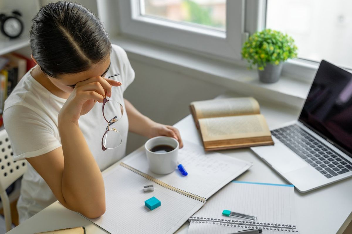 Tired woman suffering from chronic fatigue syndrome doing work at home