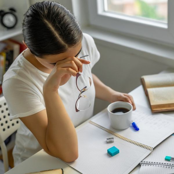 Tired woman suffering from chronic fatigue syndrome doing work at home