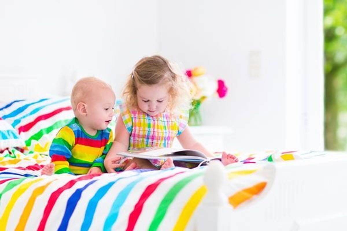 toddler and baby looking at a book