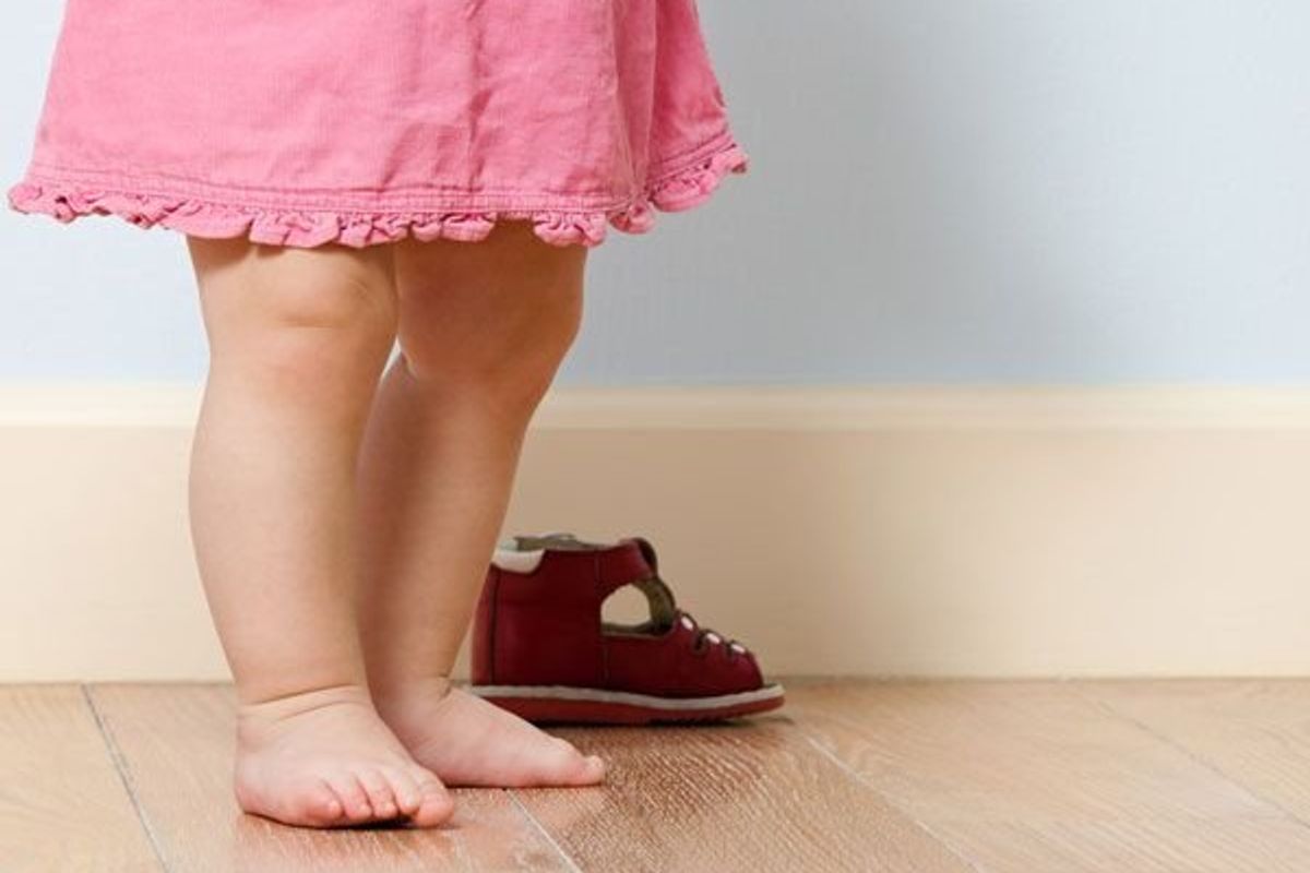 toddler standing next to a pair of shoes