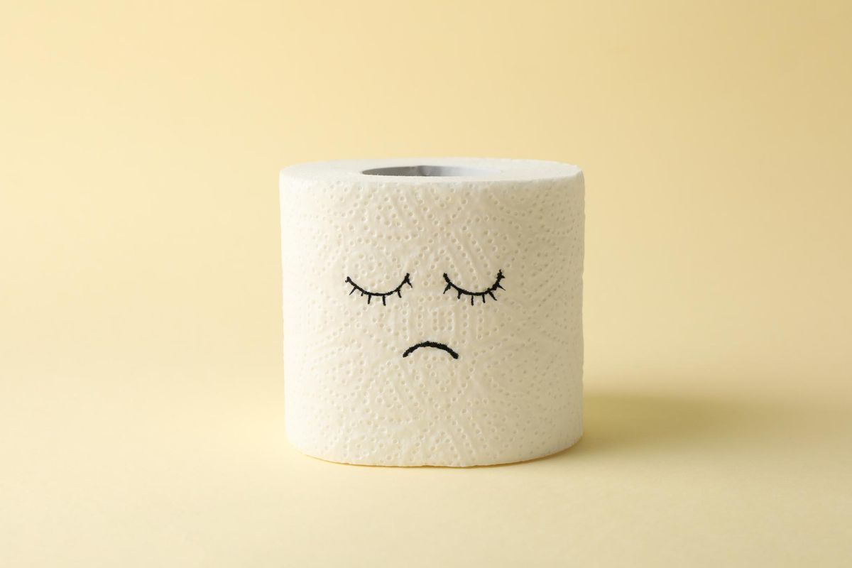 Toilet paper with sad face on beige background
