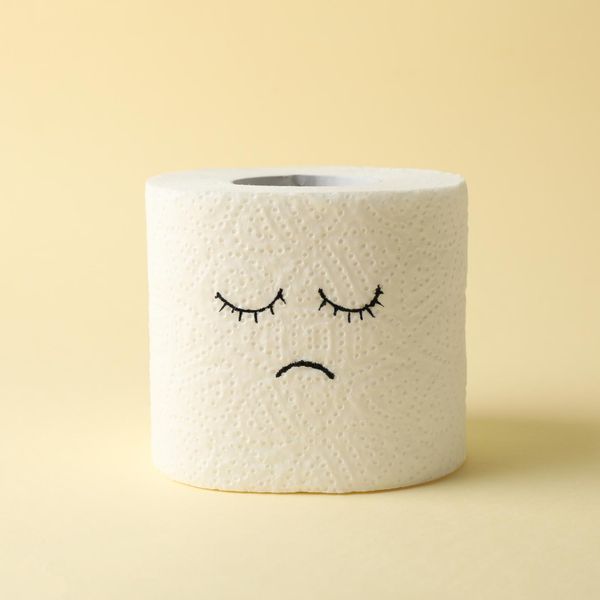 Toilet paper with sad face on beige background