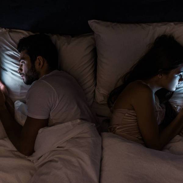Top view of young couple lying in bed at night and using smartphones