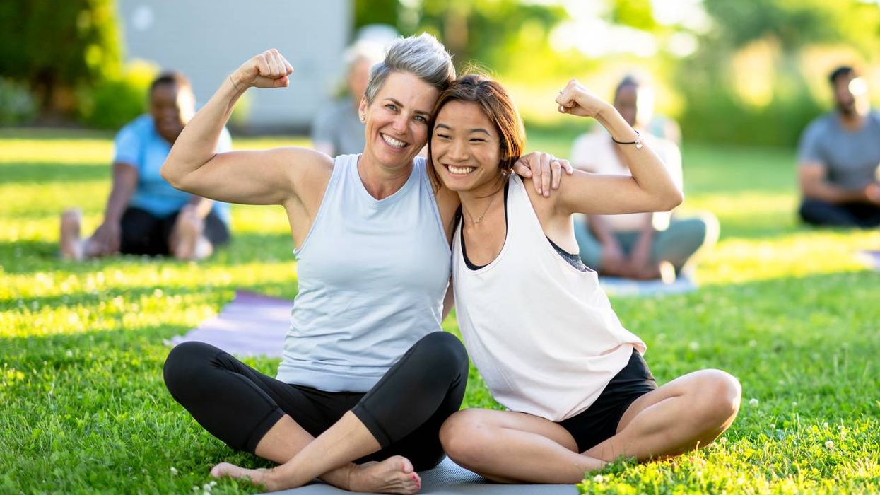 Two friends embrace and smile at an outdoor yoga class