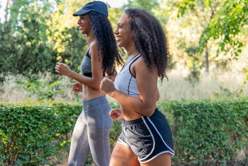 Two smiling Latinas running outdoors in a park