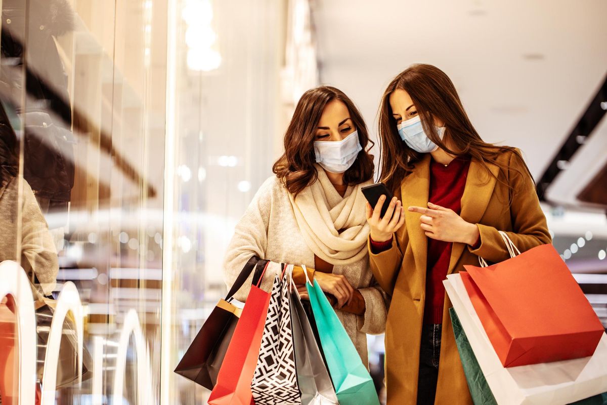 Two young girl friends in safety medical masks during shopping in the mall