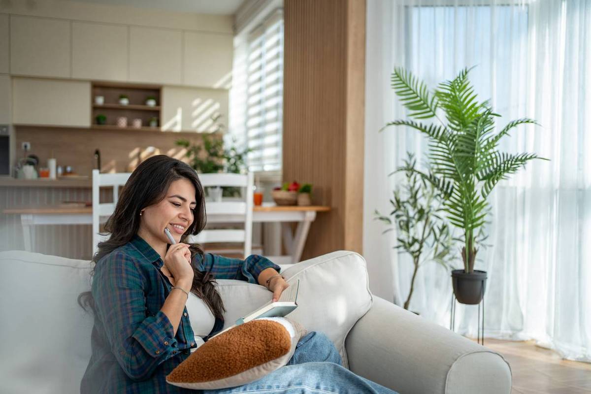 Una mujer se relaja en el sofá escribiendo en su diario