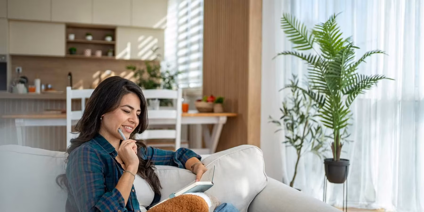 Una mujer se relaja en el sofá escribiendo en su diario