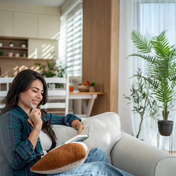 Una mujer se relaja en el sofá escribiendo en su diario