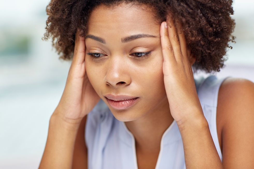 unhappy african american young woman touching her head and suffering from headache