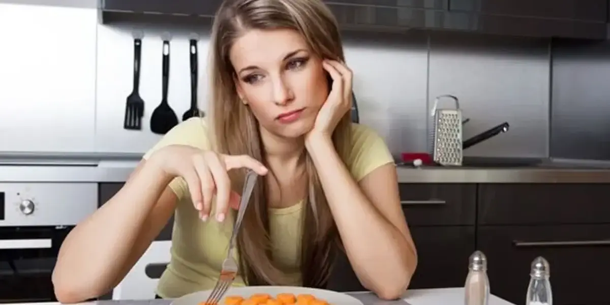 unhappy woman sitting in front of a plate of carrots