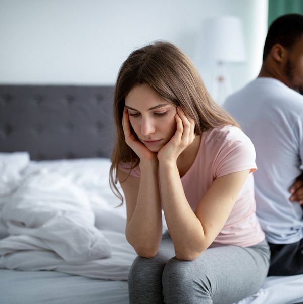 Upset Caucasian woman sitting back to back on bed with her black husband