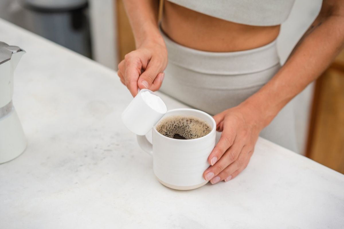 woman adding protein powder in a coffee
