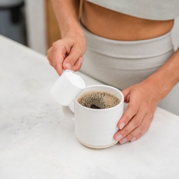 woman adding protein powder in a coffee