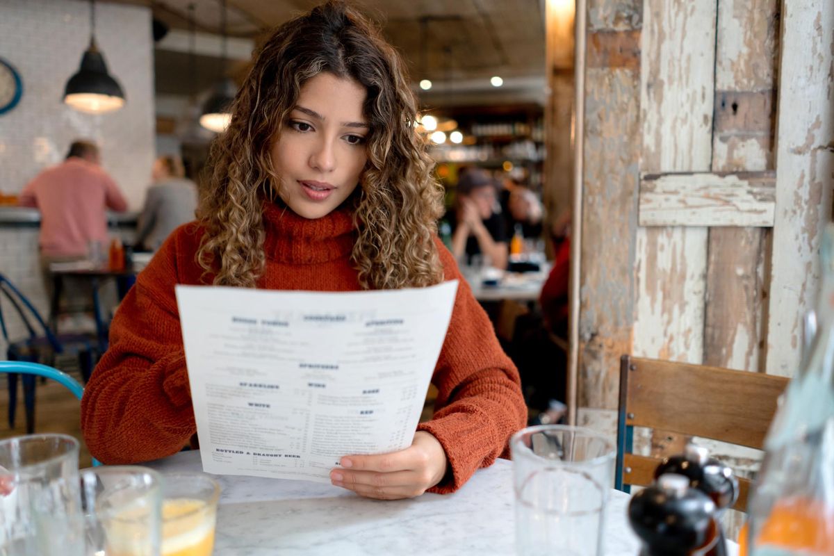 Woman at a restaurant reading the menu