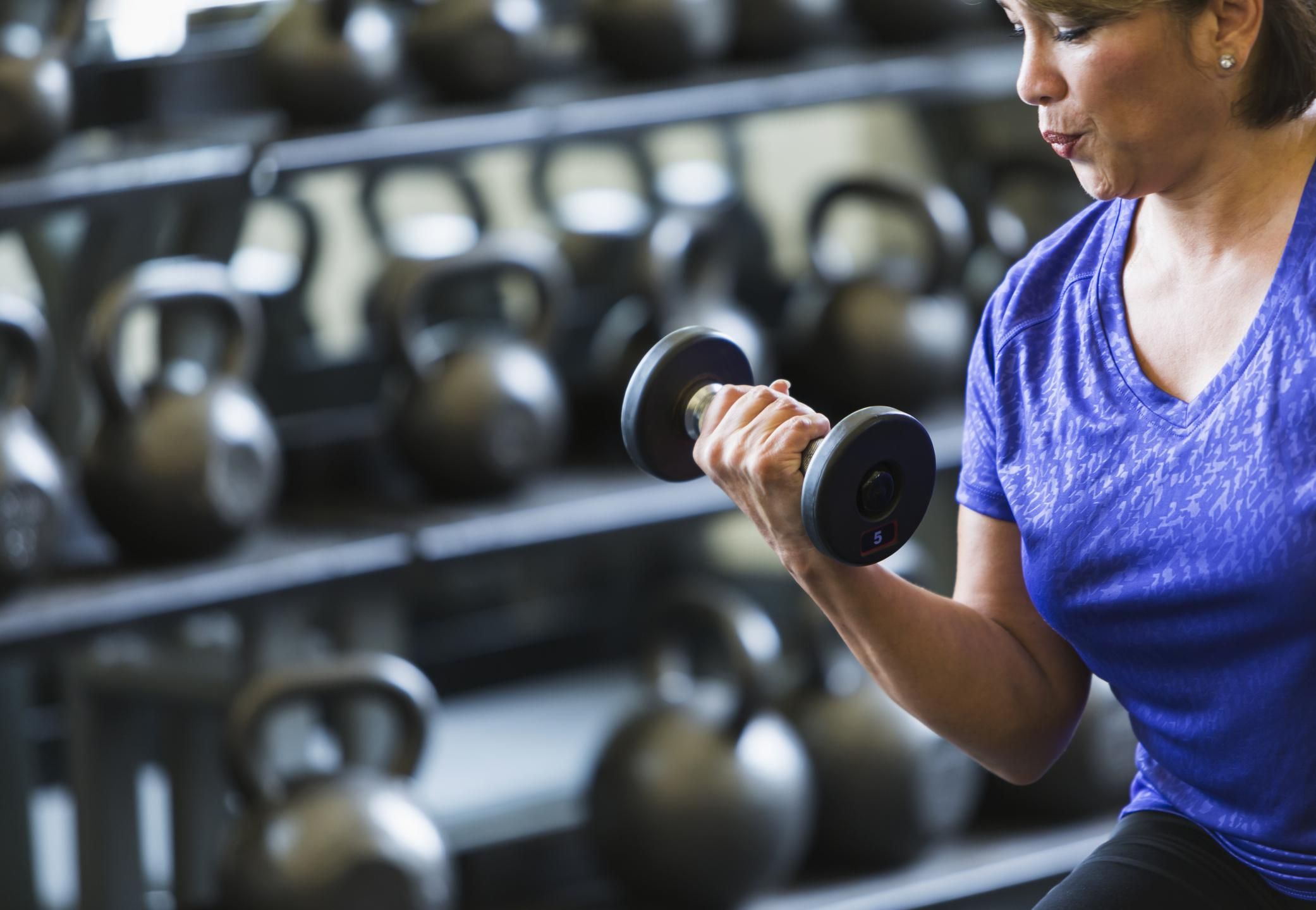 woman at gym lifting dumbbell