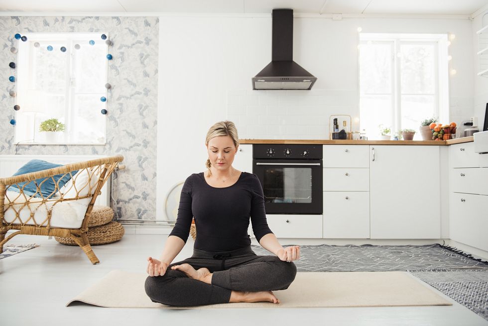 woman at home in kitchen doing yoga and meditation