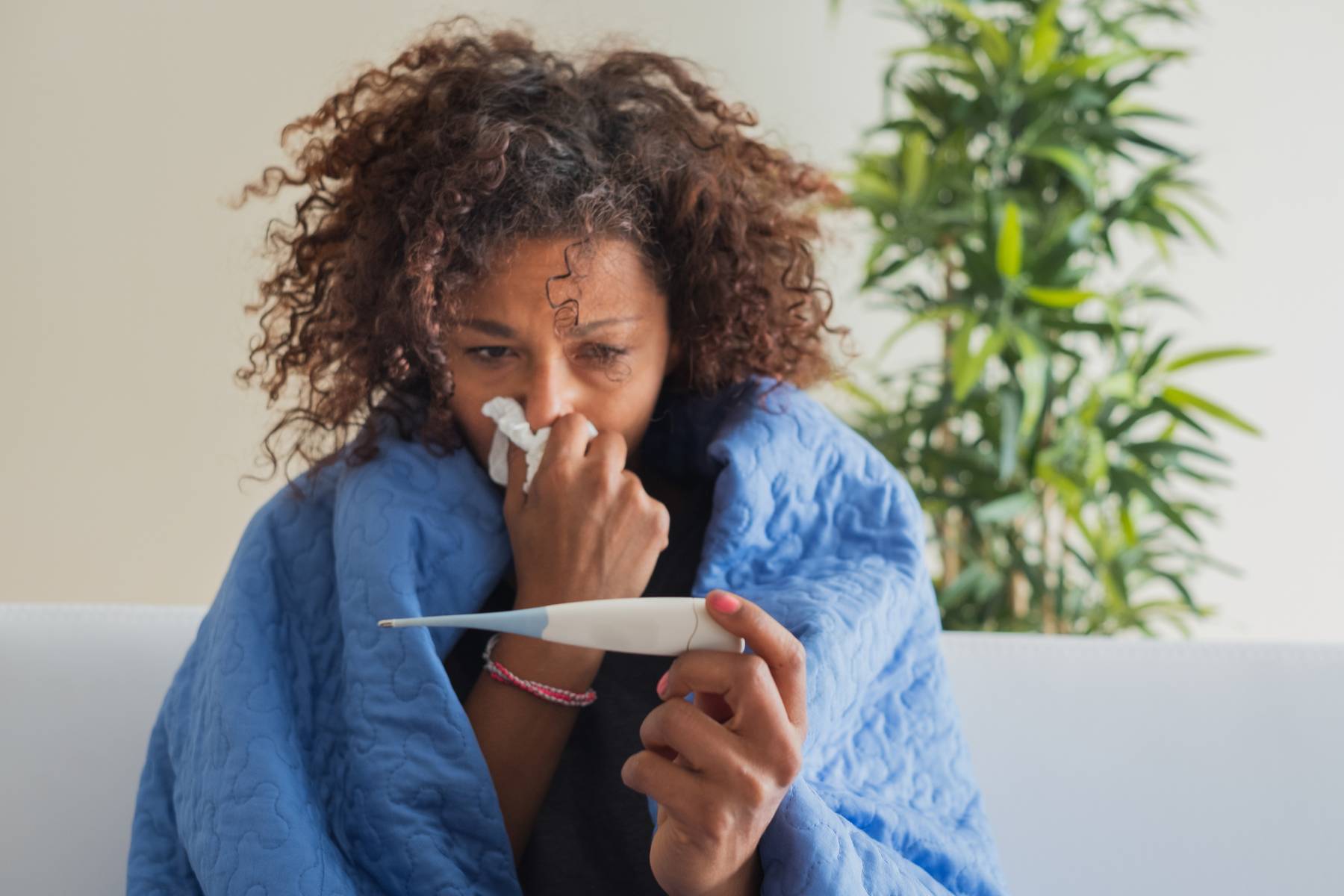 Woman blowing nose and checking body temperature