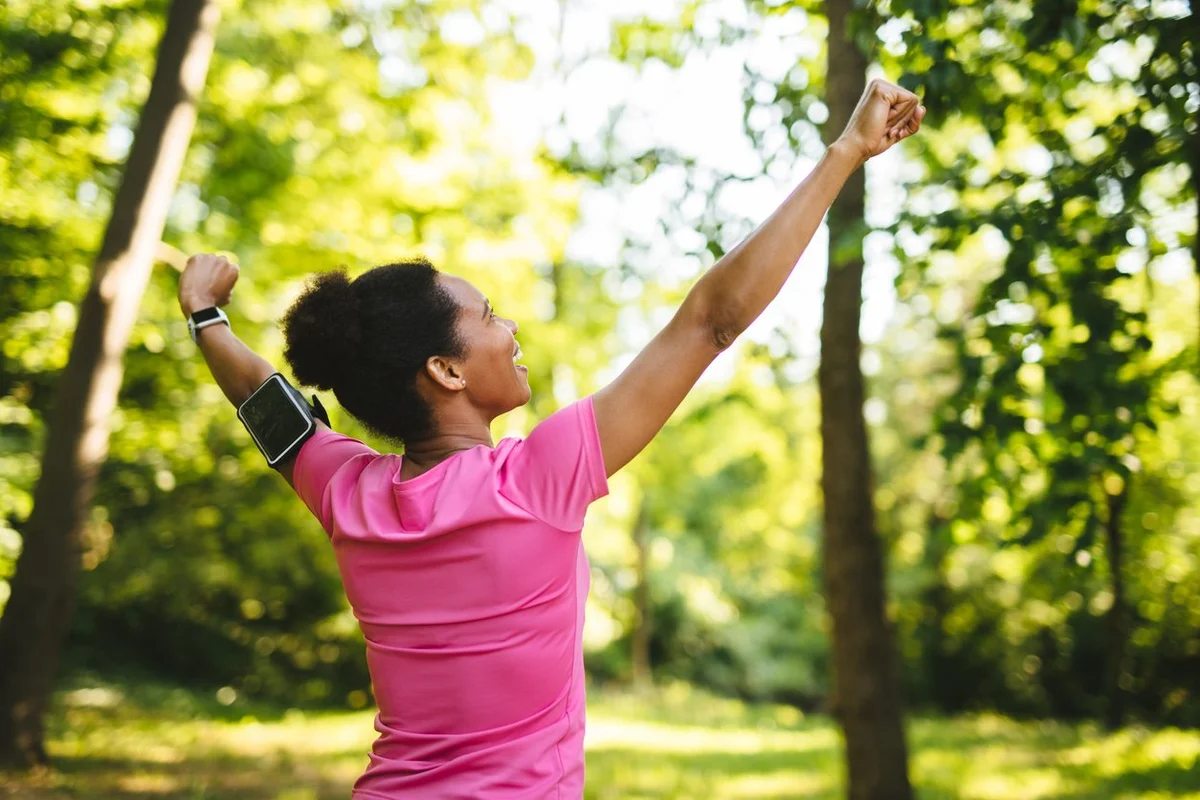 woman celebrating with arms raised after workout outdoors