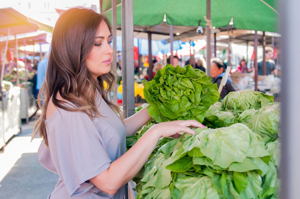woman choosing green leafy vegetables in green market