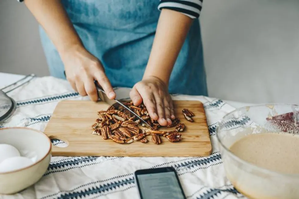 Woman chopping pecan nuts for a cake