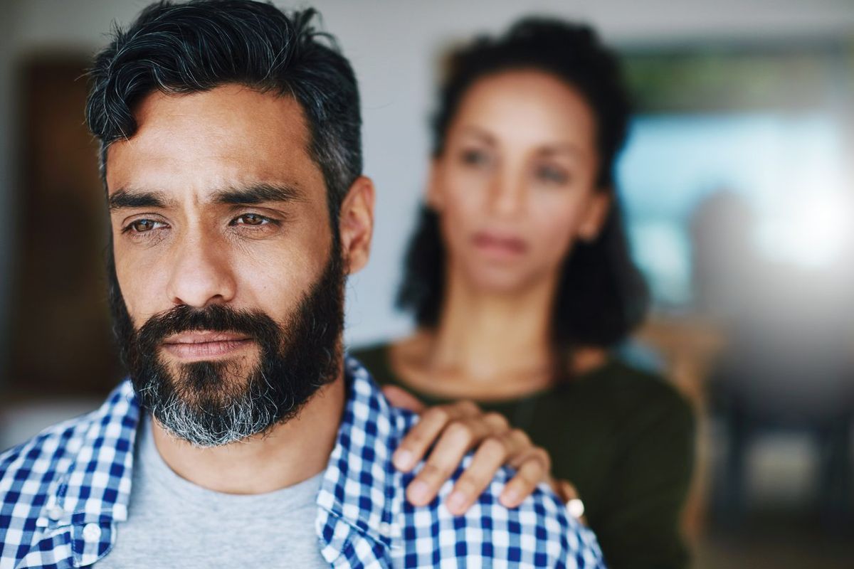woman comforting her distraught husband at home