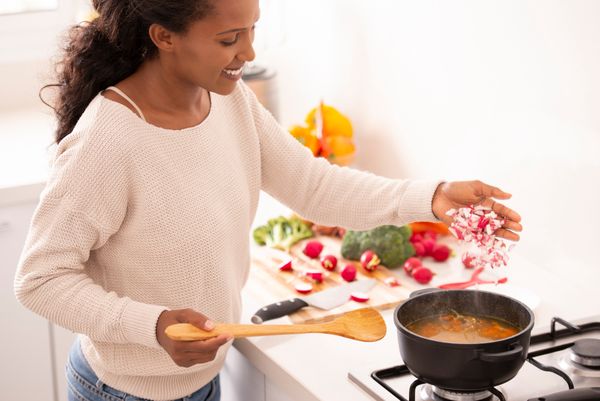 woman cooking healthy vegetable soup, preparing food at the kitchen