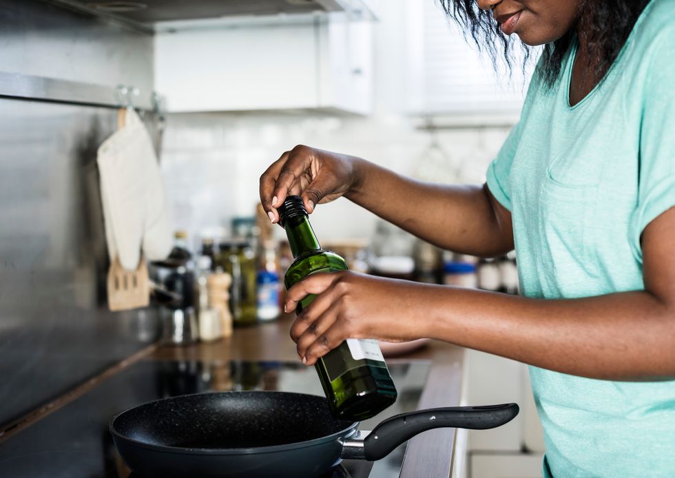 woman cooking in her kitchen, using olive oil