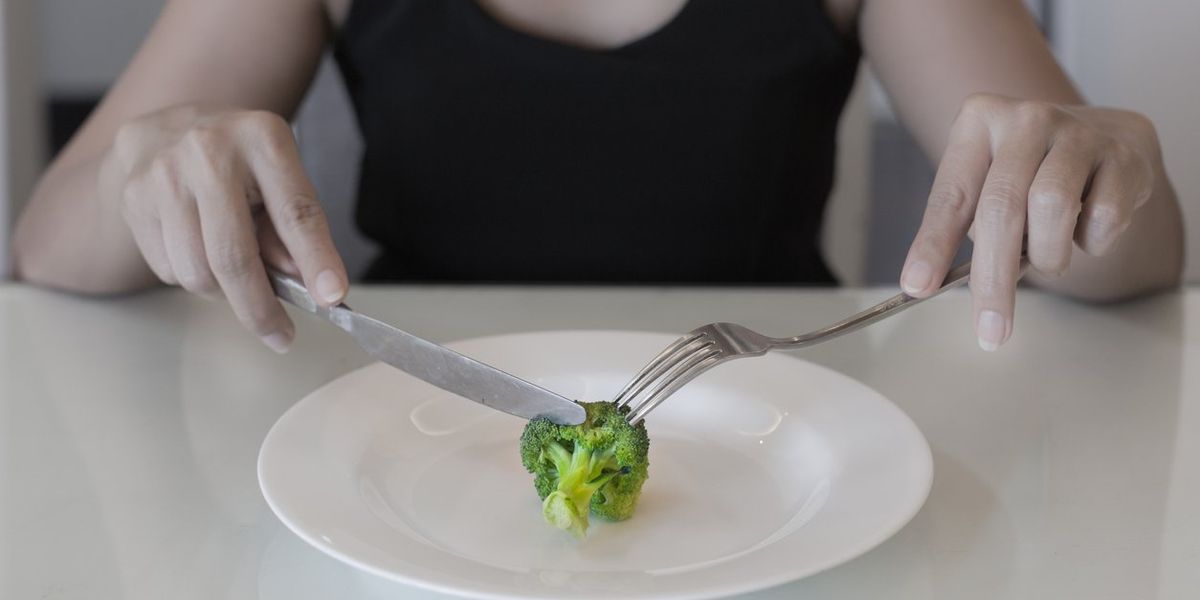 woman eating a small portion of vegatables