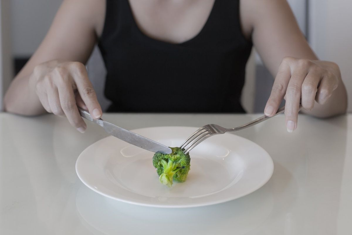 woman eating a small portion of vegatables