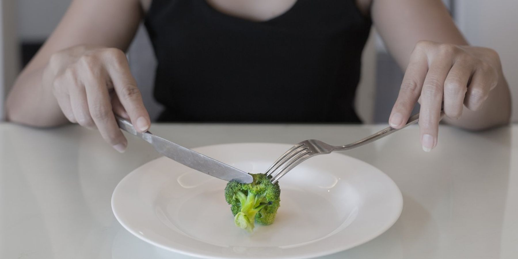 woman eating a small portion of vegatables
