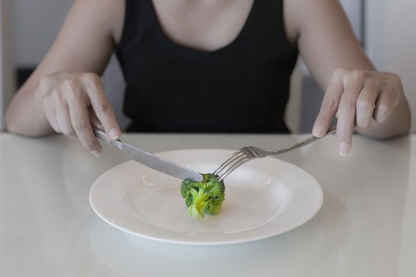 woman eating a small portion of vegatables