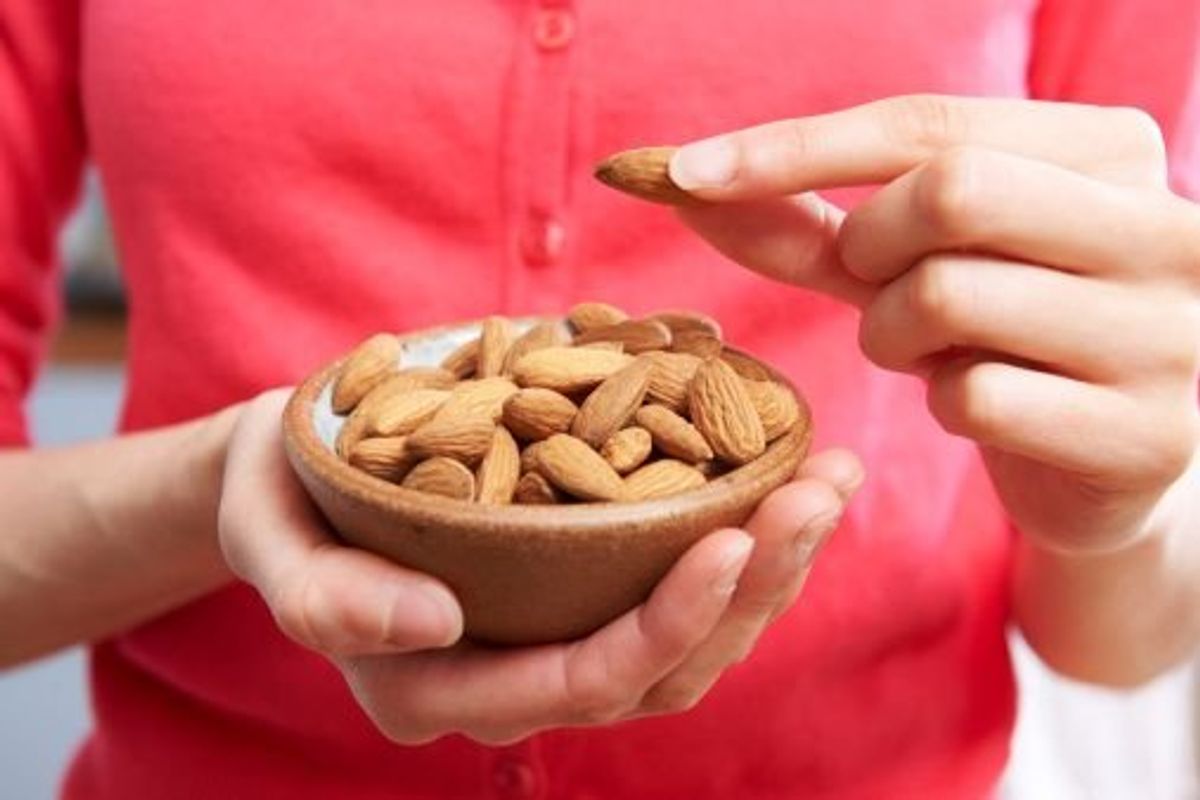 woman eating bowl of nuts