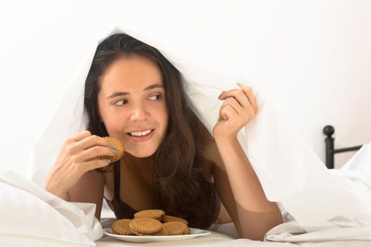 woman eating cookies in bed