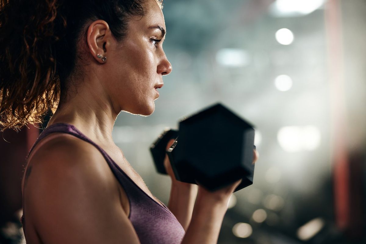 woman exercising with dumbbell during sports training in a gym