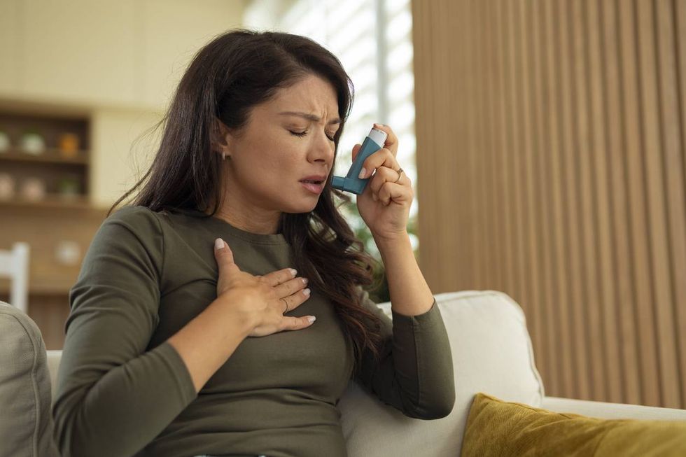 woman experiencing asthma attack using inhaler at home