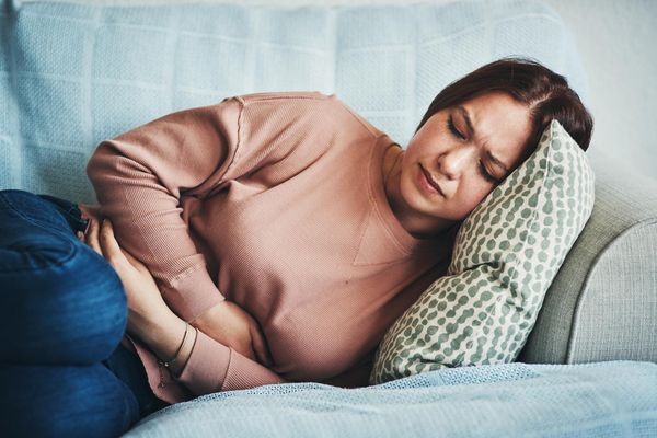 woman experiencing stomach pain while lying on the sofa at home