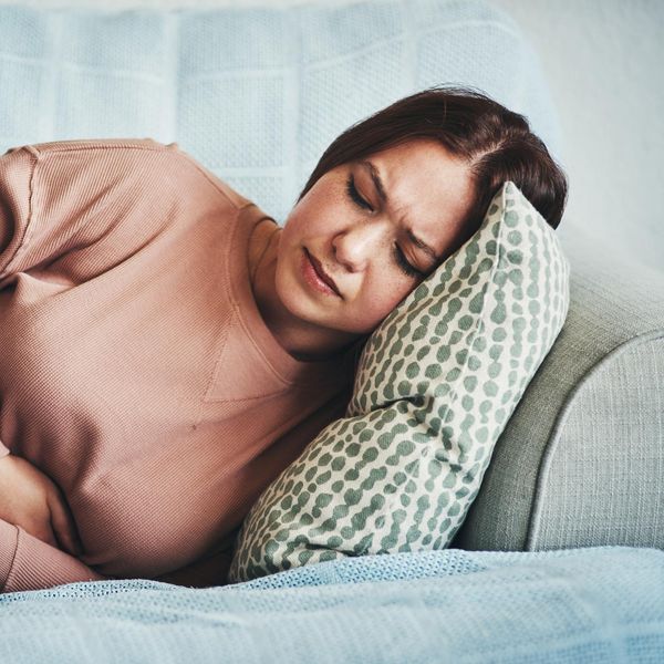 woman experiencing stomach pain while lying on the sofa at home