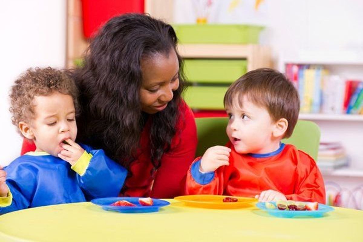woman feeding children in daycare