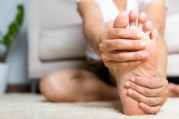 woman feeling pain in her foot at home