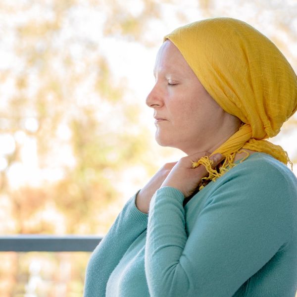 woman from behind putting a yellow scarf on her head because she has Urothelial Bladder cancer and worried