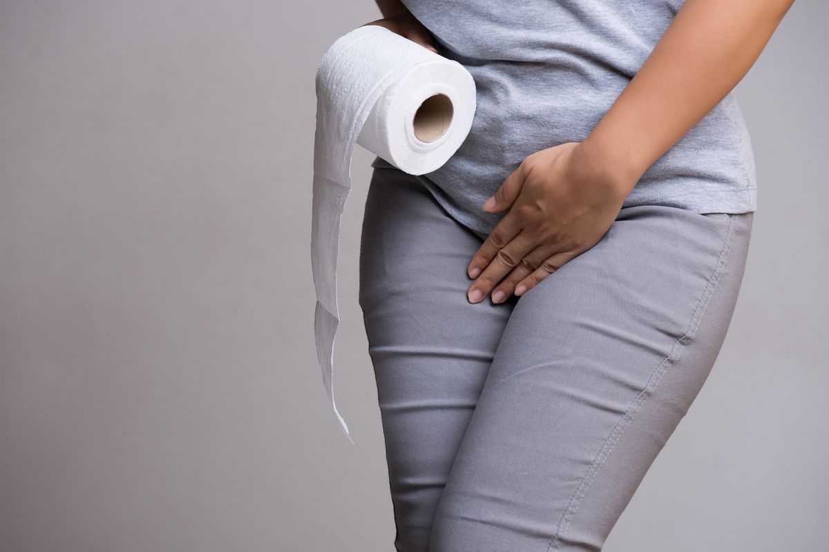 Woman hand holding her crotch and toilet paper suffering from overactive bladder