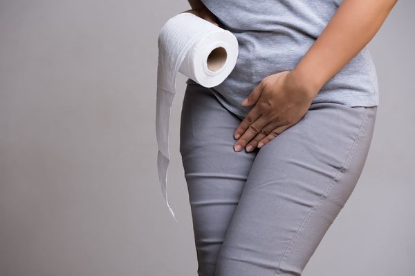 Woman hand holding her crotch and toilet paper suffering from overactive bladder