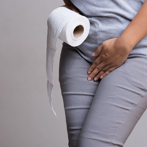 Woman hand holding her crotch and toilet paper suffering from overactive bladder