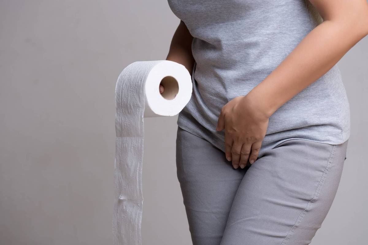 Woman hand holding her crotch and toilet paper suffering from overactive bladder