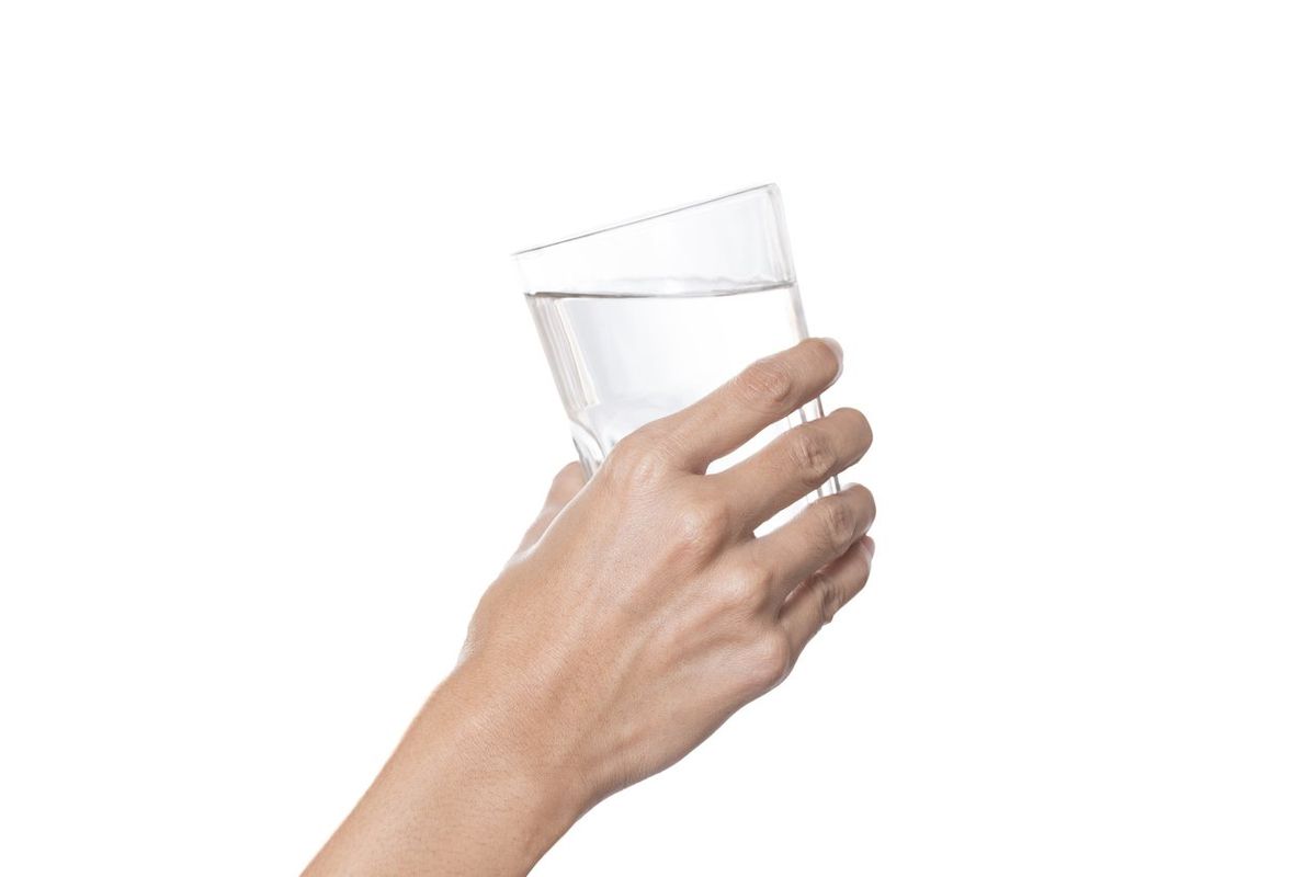 Woman hand with glass of water isolated on white background