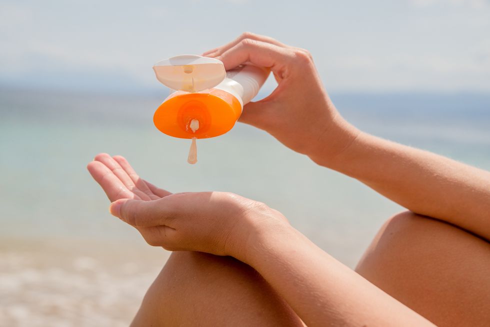 Woman hands putting sunscreen from a suncream bottle