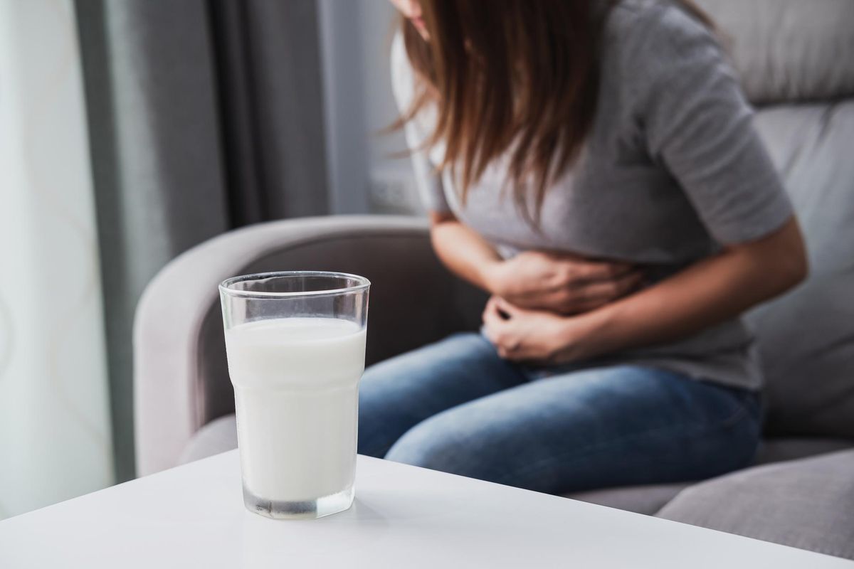 Woman having bad stomach ache with a glass of milk