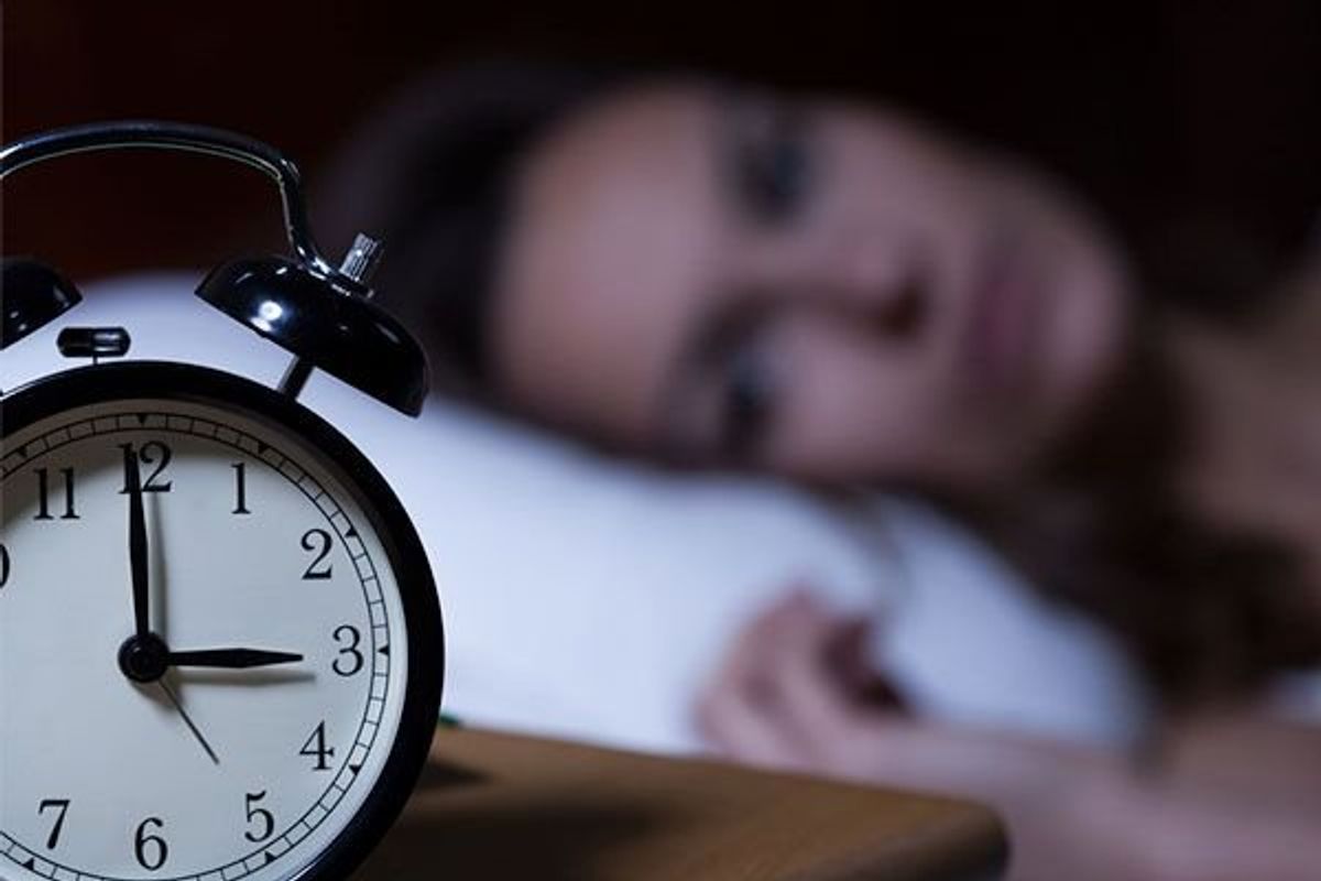 woman having trouble sleeping looking at the clock