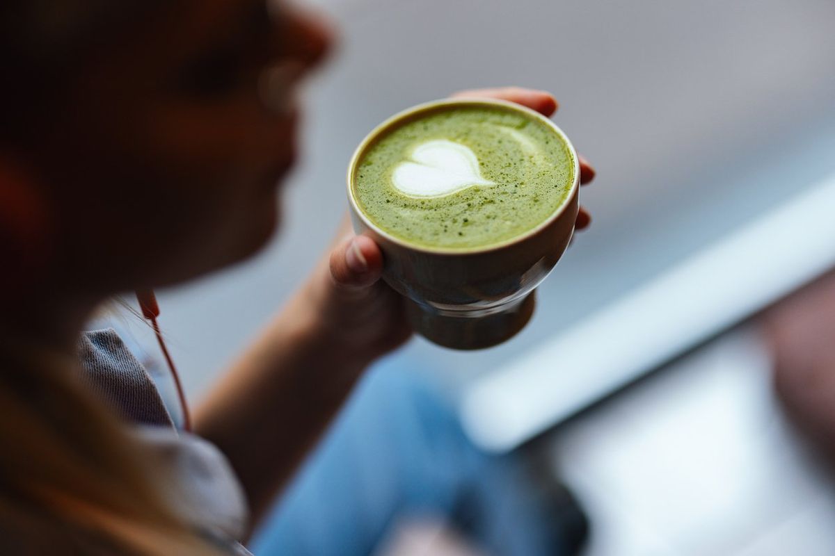 woman holding a cup of matcha tea with green foam